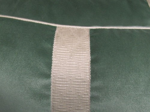 Tape trim machine applied on each side of a rectangular  pillow. Small cord/rope in seam. 